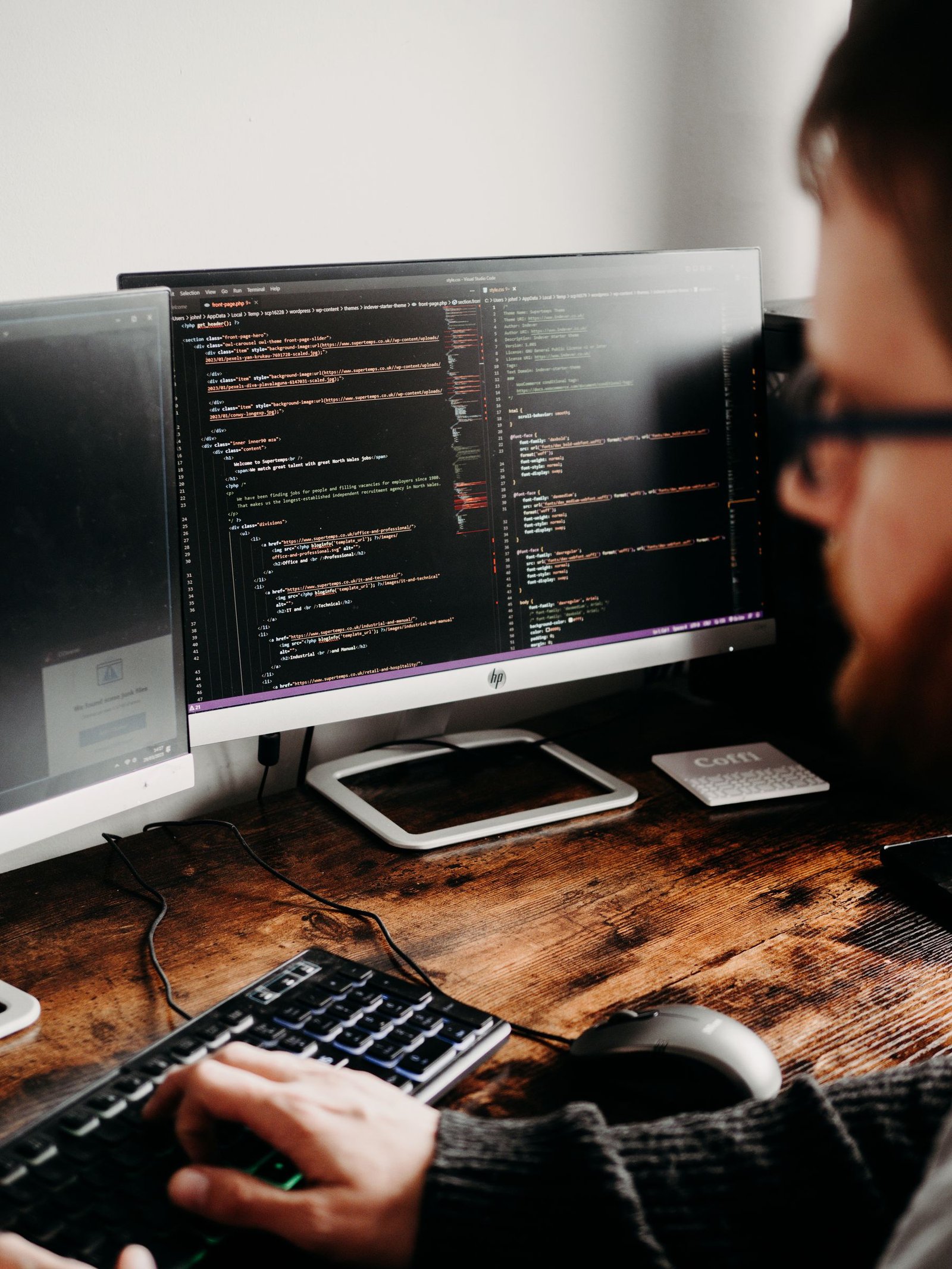 Software developer coding across multiple monitors in a focused modern workspace